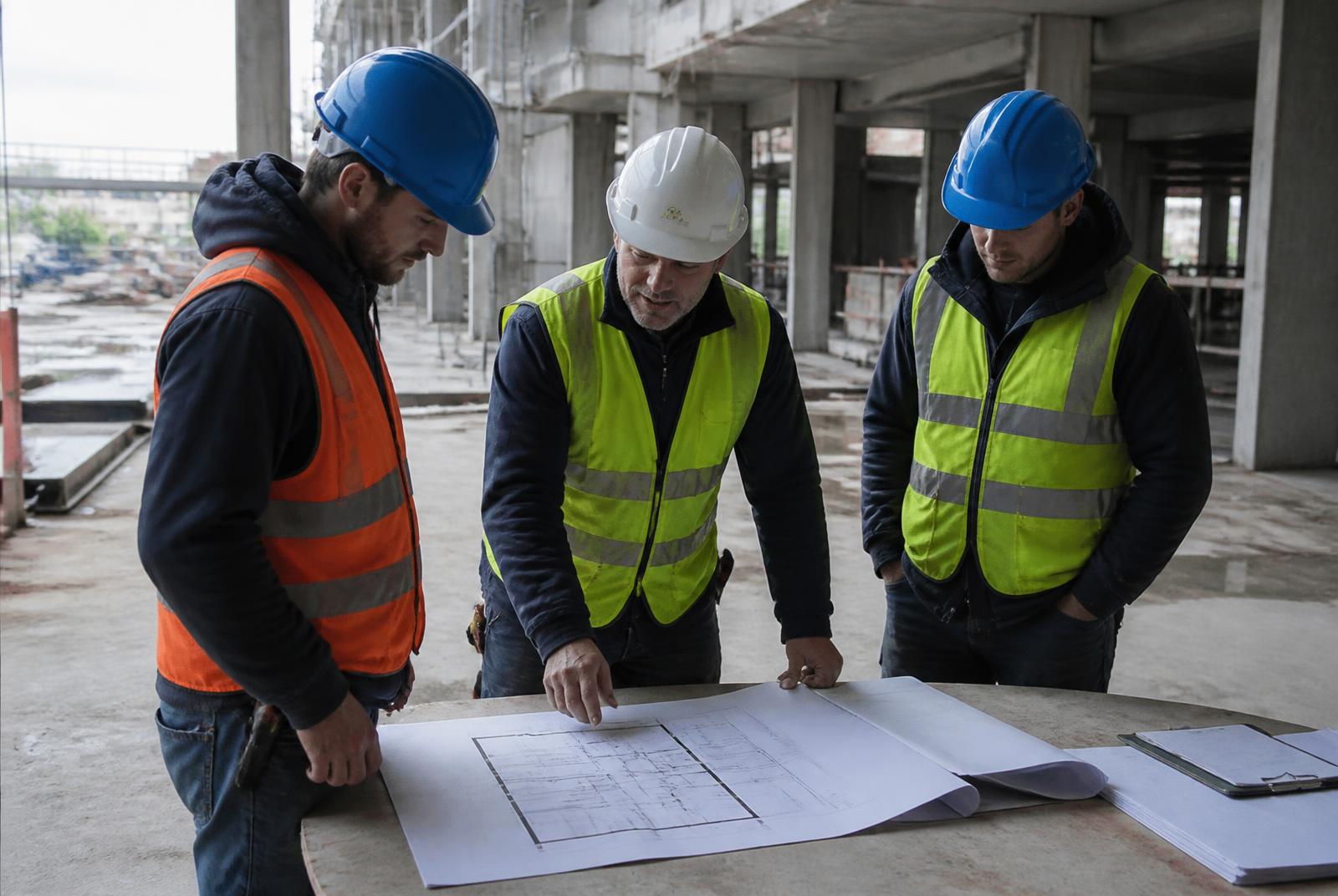 Reunião técnica em obra com equipe analisando plantas